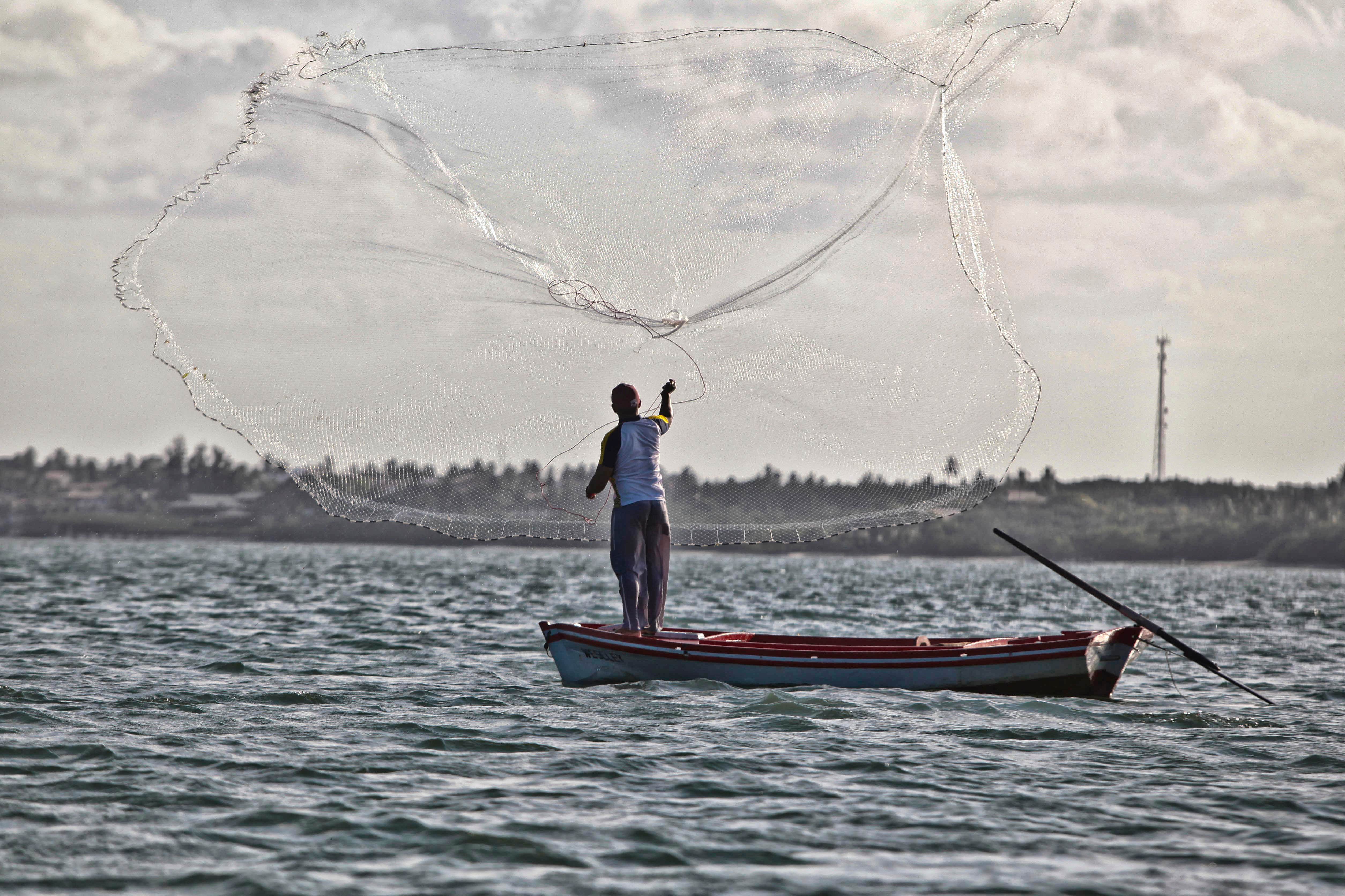 Pescador lançando a tarrafa no rio Jaguaribe, no Ceará